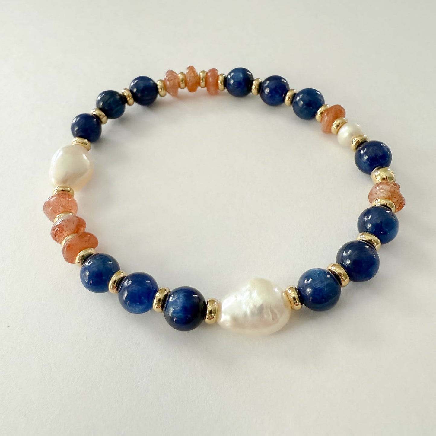 Orange blue and white stretch bracelet handcrafted with lapis, sandstone, freshwater baroque pearl and gold-filled beads.