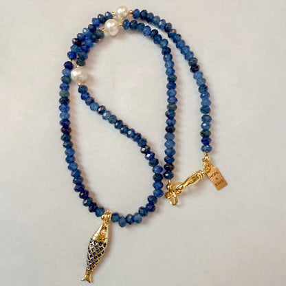 Tiny blue beaded natural gemstone necklace with gold-filled fish charm and gold-filled clasp. The piece features accents of natural freshwater pearls and is handcrafted by Hope and Raye in Atlanta, Georgia.