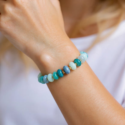 Blue quartz stretch bracelet with gold beads on model wrist ￼