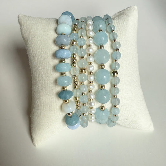 Bracelet stack of six beta gemstones on stretch material. Aquamarine, opal pearl and gold-fille bracelet set. 