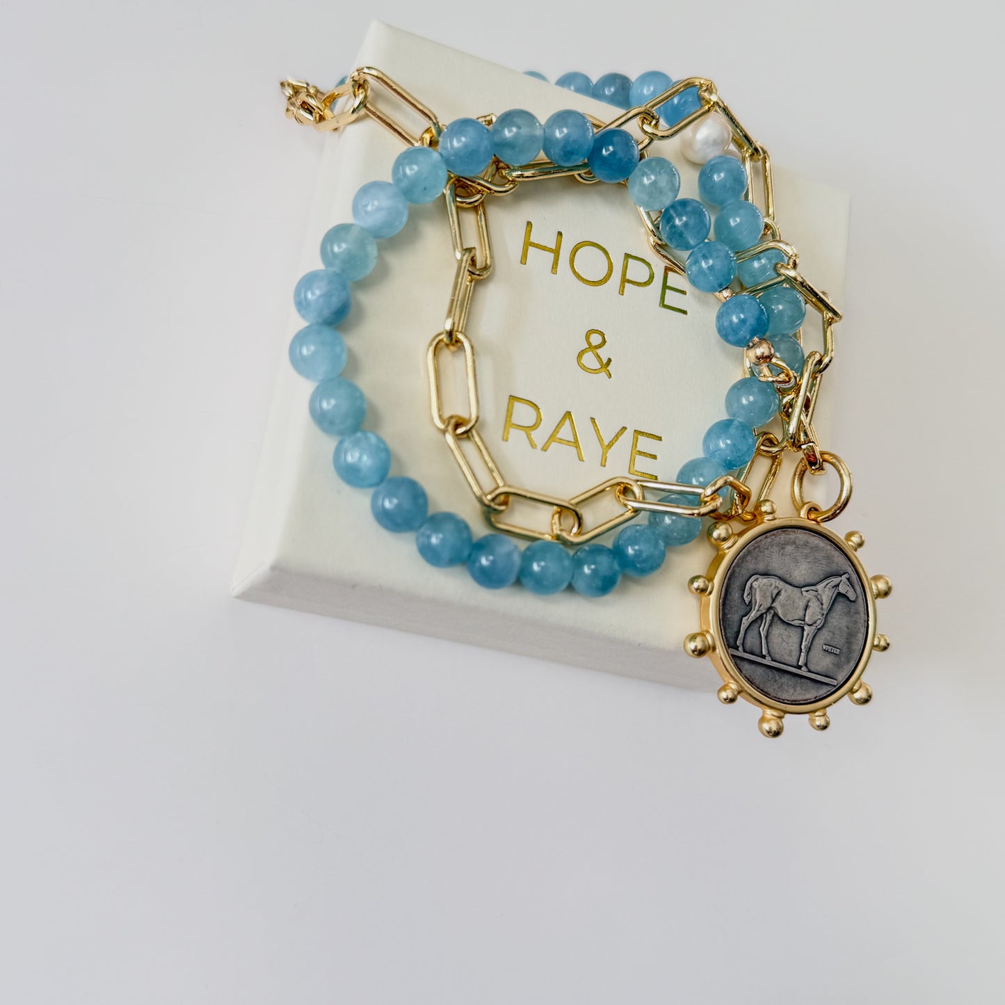 24 inch Aquamarine and gold paperclip chain necklace with bold horse pendant and gold clasp by Hope and Raye.