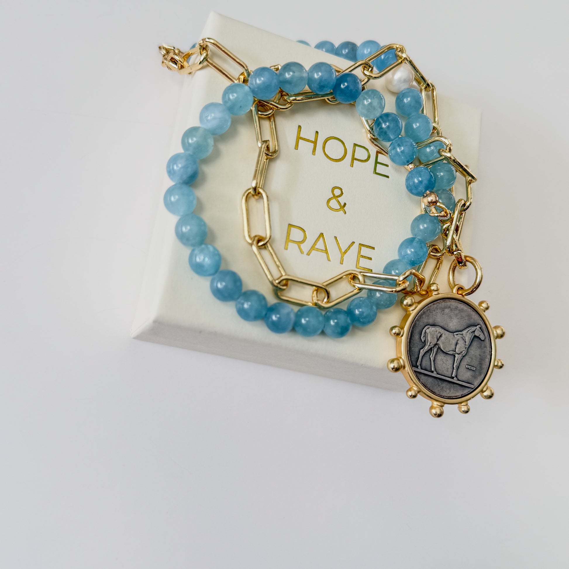 24 inch Aquamarine and gold paperclip chain necklace with bold horse pendant and gold clasp by Hope and Raye.