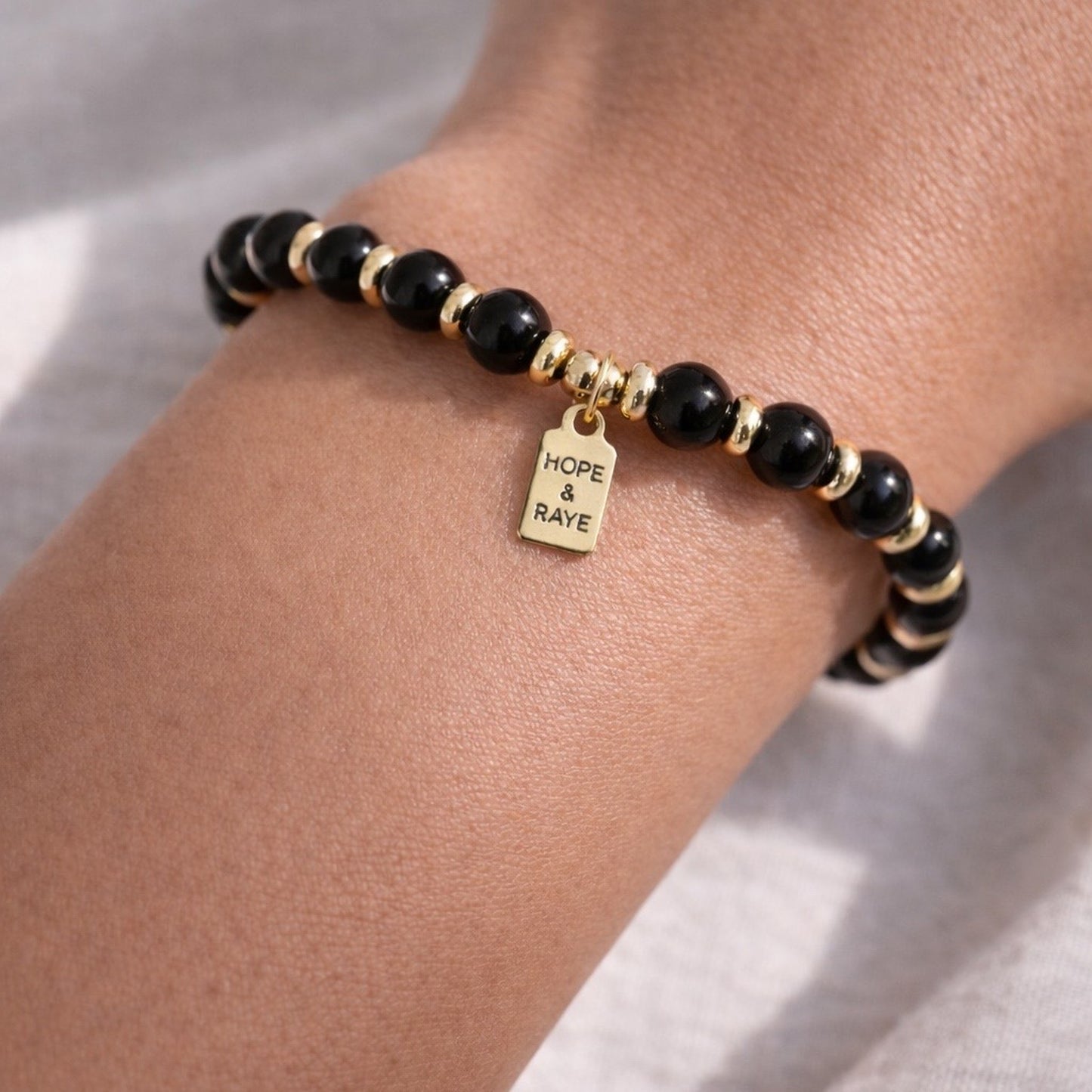 Black beaded oxide gemstone bracelet with gold discs. Layering bracelet for every day wear. Handcrafted with natural gemstones and 18k gold beads in Atlanta. 