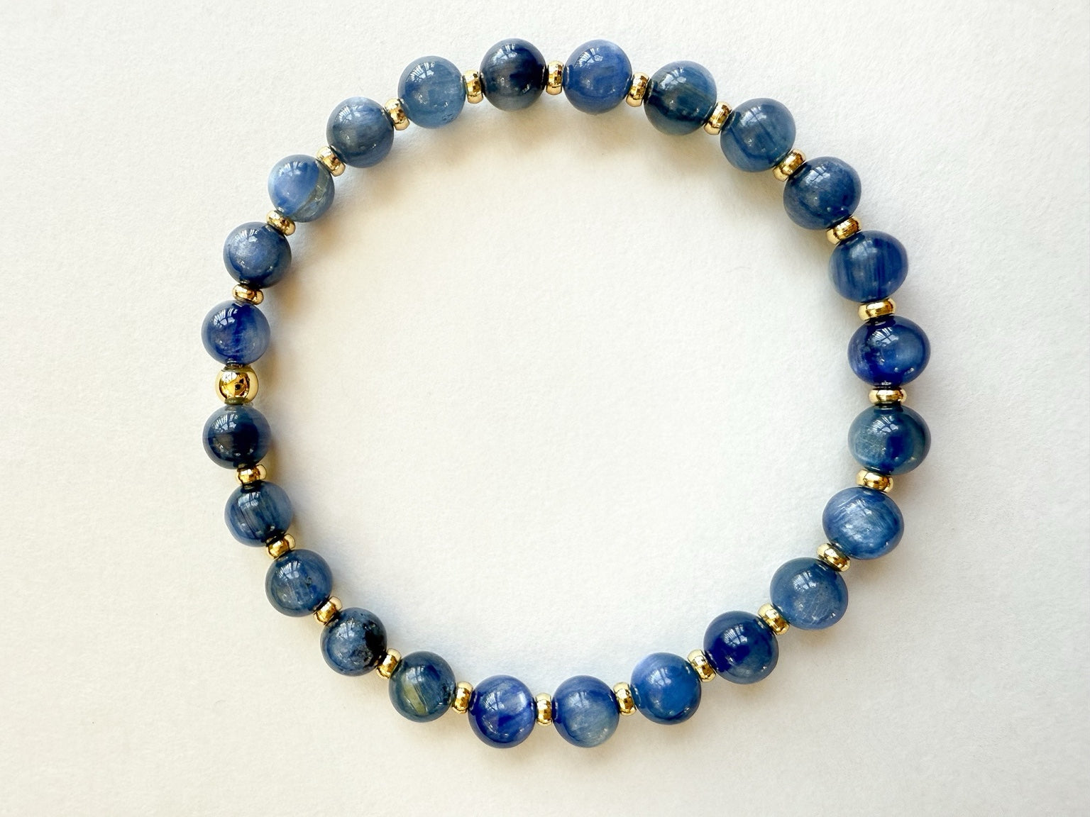 Blue gemstone and gold stretch bracelet handcrafted with smooth round natural blue gemstones and small gold-filled disc beads. Strung on durable stretch cord. HOPE & RAYE.