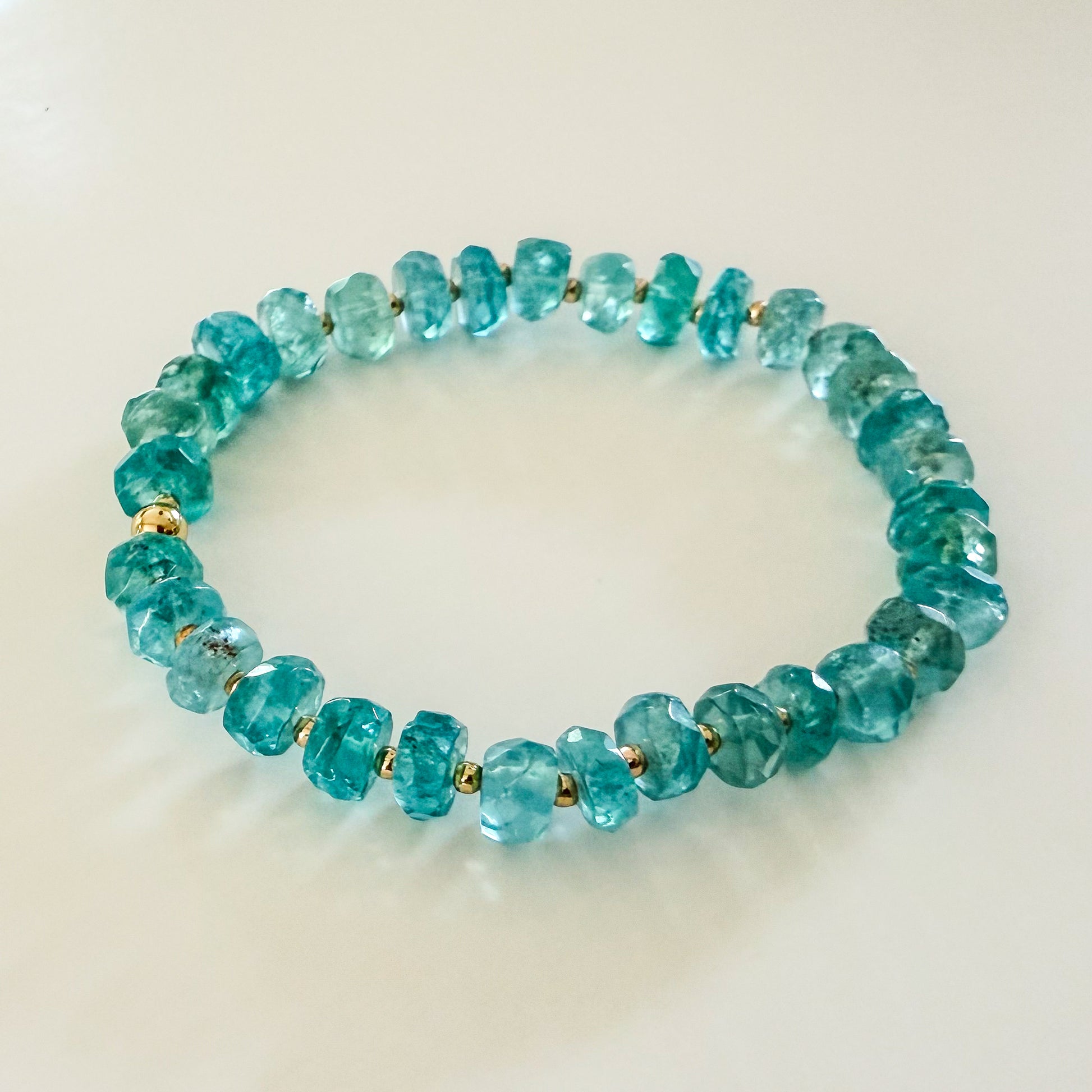 Blue apatite natural gemstone beaded stretch bracelet with gold beads. Handcrafted for layering and wearing solo. 