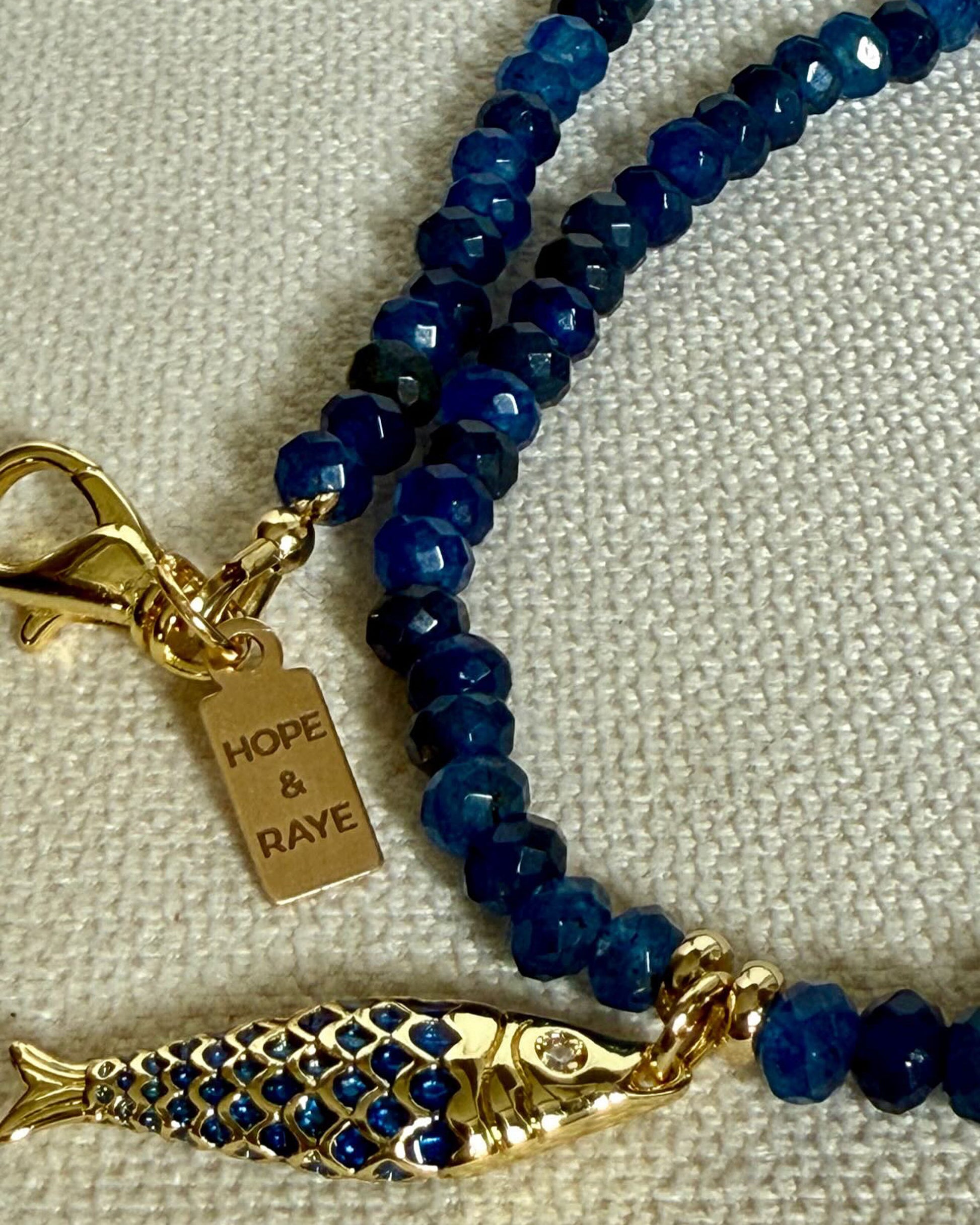 Tiny blue beaded gemstone necklace with gold Fish charm and gold clasp. Handcrafted in small batches in Atlanta, Georgia by Hope and Raye. 