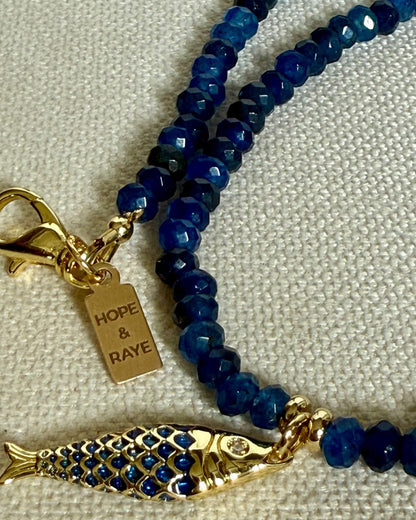 Tiny blue beaded gemstone necklace with gold Fish charm and gold clasp. Handcrafted in small batches in Atlanta, Georgia by Hope and Raye. 