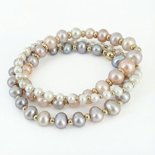 Pink, white, gray, and soft purple bracelet stack featuring three stretch bracelets made with natural freshwater pearls in varied sizes, finished with small gold-filled disc beads. Handcrafted pearl bracelet set by HOPE & RAYE.