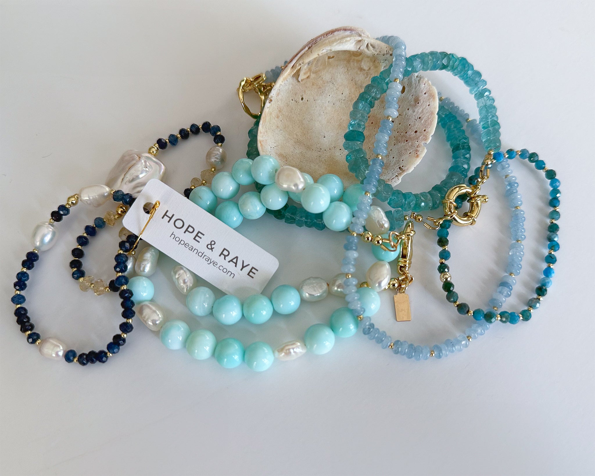 Hope and Raye jewelry collection necklaces and bracelets on seashells.